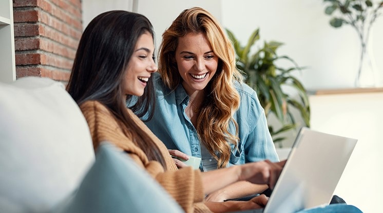 two women smiling at computer screen